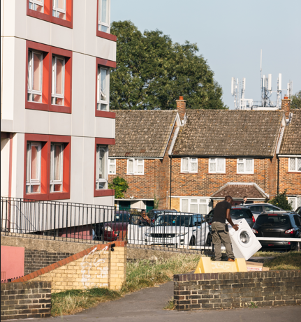 Housing Image shows a mixture of housing; to the left hand side, a tower block, and in the background, a row of terraced housing likely in an inner-city area. Cars are parked next to the housing.