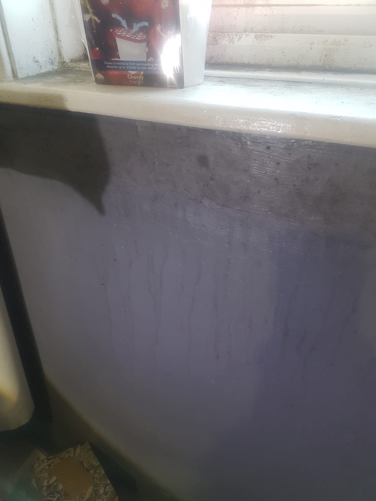 Image shows condensation from damp inside, dripping down a wall under a windowsill.